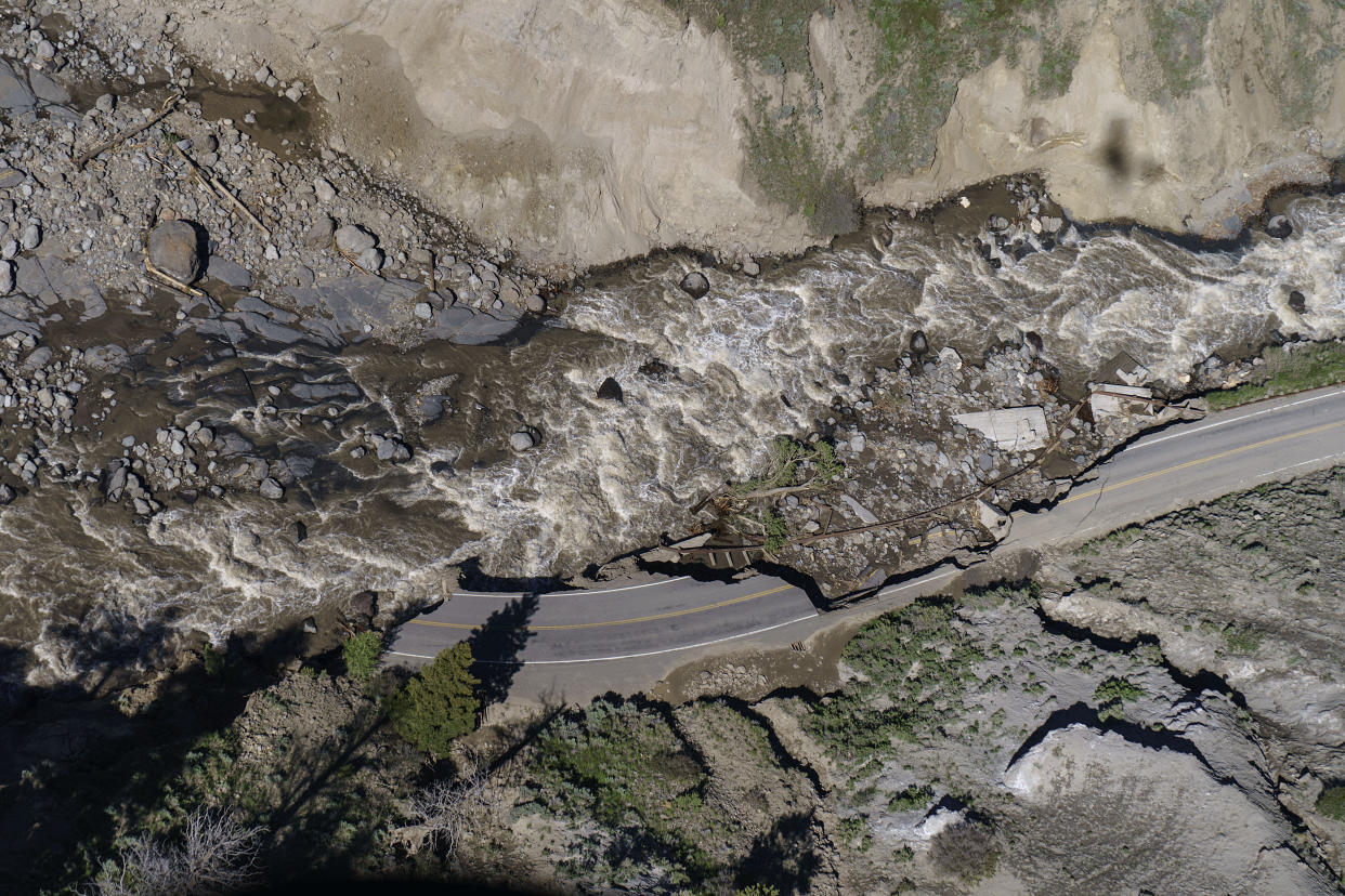 Receding floodwaters flow past sections of North Entrance Road washed away at Yellowstone National Park in Gardiner, Mont., Thursday, June 16, 2022. Yellowstone officials are hopeful that next week they can reopen the southern half of the park, which includes Old Faithful geyser. Park officials say the northern half of the park, however, is likely to remain closed all summer, a devastating blow to the local economies that rely on tourism. (AP Photo/David Goldman)