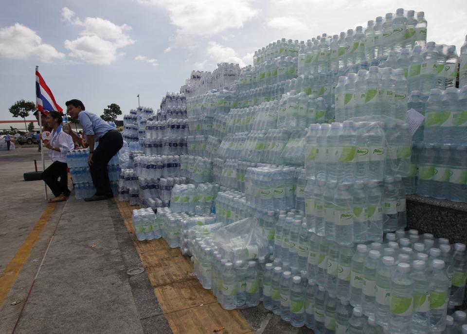 Anti-government protesters pose with stacks of bottled water during a rally at a government complex in Bangkok