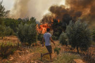 A man walks toward wildfires in Kacarlar village near the Mediterranean coastal town of Manavgat, Antalya, Turkey, Saturday, July 31, 2021. The death toll from wildfires raging in Turkey's Mediterranean towns rose to six Saturday after two forest workers were killed, the country's health minister said. Fires across Turkey since Wednesday burned down forests, encroaching on villages and tourist destinations and forcing people to evacuate. (AP Photo)