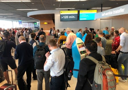 Passengers and staff wait at Amsterdam Schiphol airport