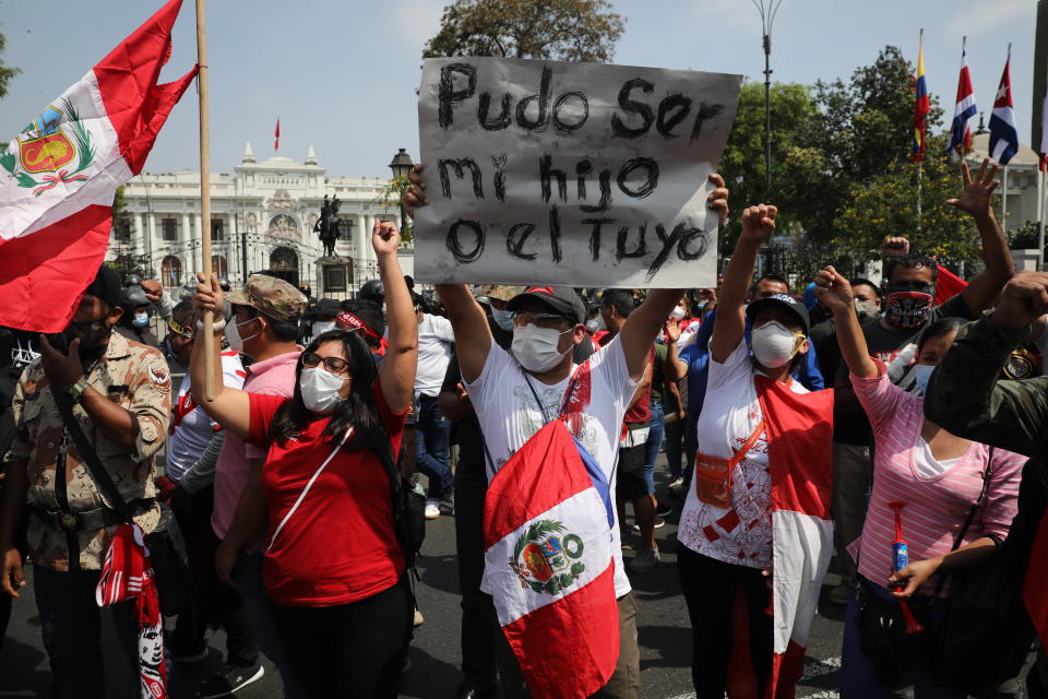 People demonstrate in favor of democracy and against corruption outside Congress in Lima, Peru, Monday, Nov. 16, 2020, one holding the Spanish message "It could have been my son or yours," referring to two students killed during weekend protests. Peru's political turmoil took a turn Sunday when interim leader Manuel Merino quit and Congress couldn't decide on his replacement, leaving the nation without a president and in crisis less than a week after legislators removed President Martín Vizcarra. (AP Photo/Rodrigo Abd)