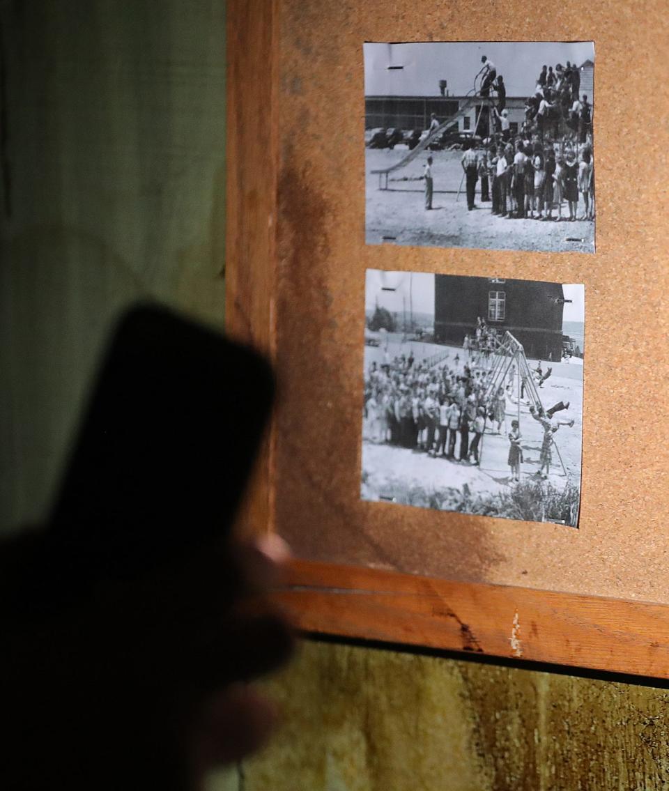 Dave Shonk shows the old photographs hanging on a bulletin board inside the Akron Haunted Schoolhouse that show the building when it was still used as a school.