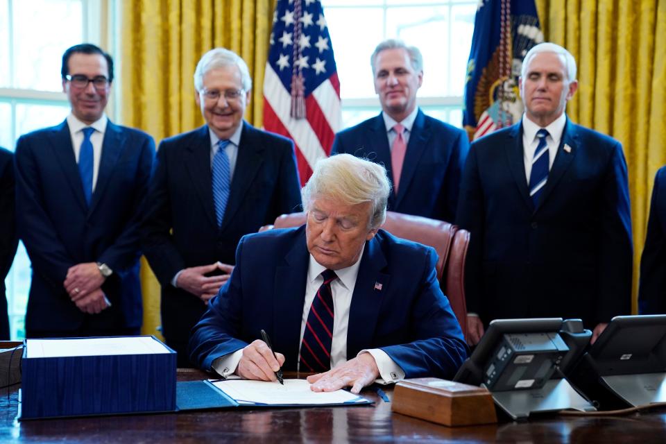 President Donald Trump signs the coronavirus stimulus relief package, at the White House on Friday.