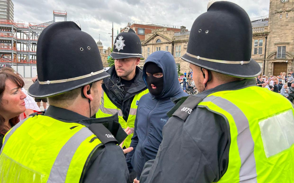 man wearing a balaclava is arrested by police as security is tightened ahead of a planned protest