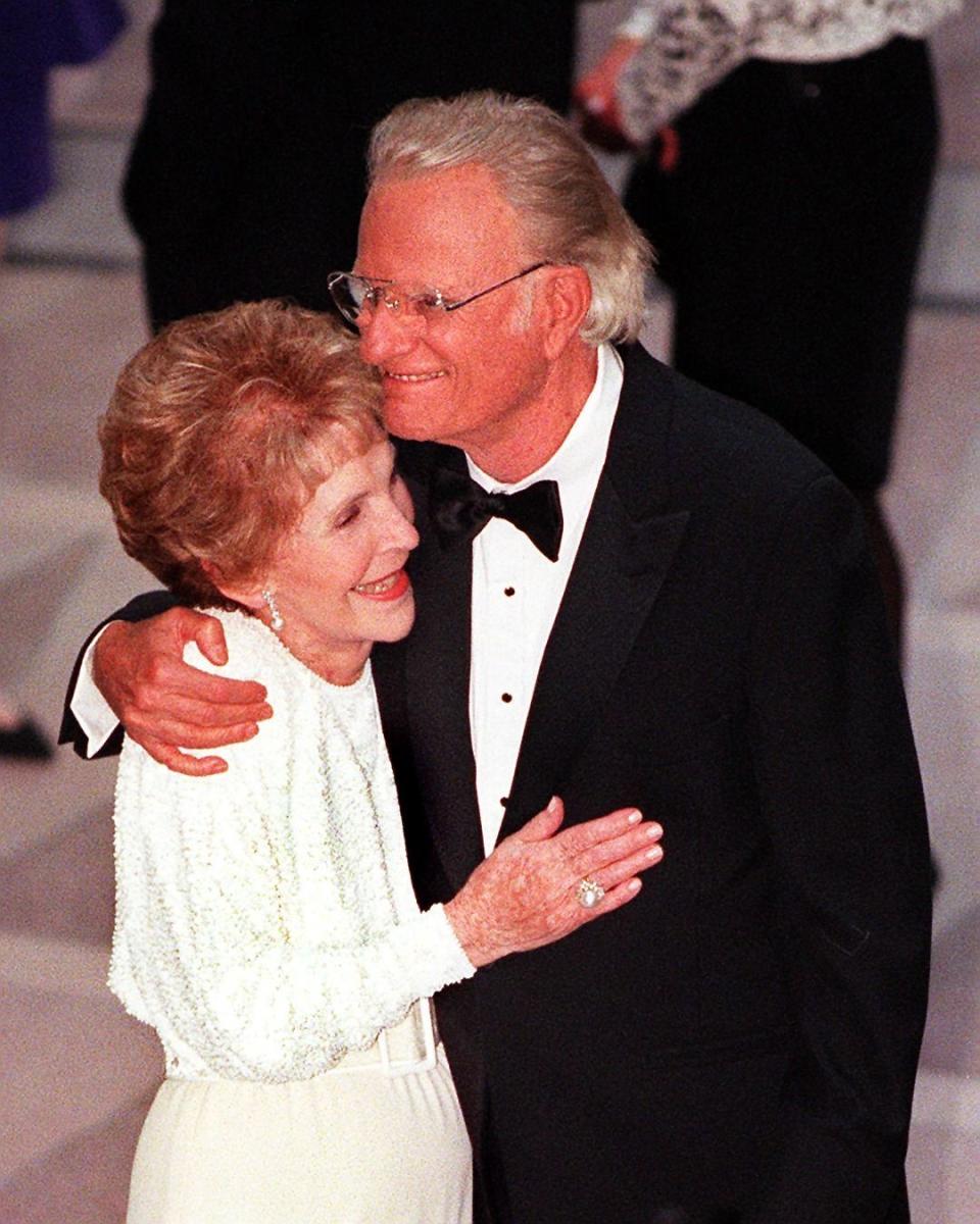 WASHINGTON, :  Former US First Lady Nancy Reagan (L)  and Reverend Billy Graham embrace during the gala dedication of the Ronald Reagan Building and International Trade Center 05 May in Washinghton, DC.  Reagan, 87, was not present at the ceremony and has not appeared in public since he announced in 1994 that he had Alzheiner's disease.     AFP PHOTO   Tim SLOAN (Photo credit should read TIM SLOAN/AFP/Getty Images)