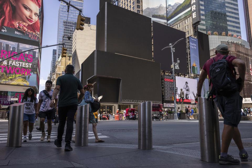 Pedestrians walk by blacked out screens, due to a global technology outage, in Times Square, Friday, July 19, 2024, in New York. (AP Photo/Yuki Iwamura)