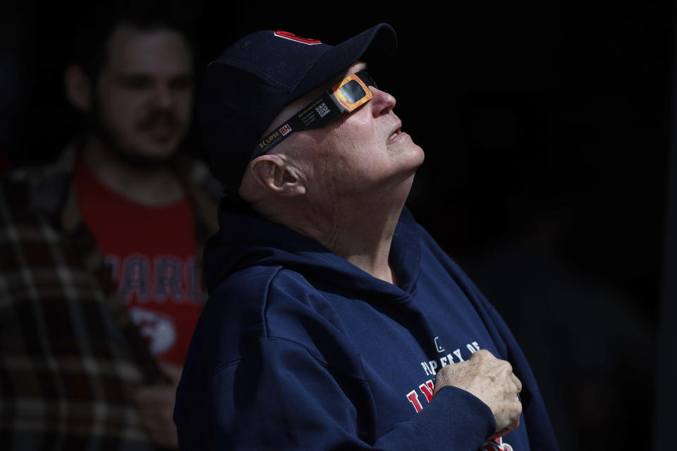 A Cleveland Guardians fan uses special glasses to watch the total solar eclipse, Monday, April 8, 2024, in Cleveland. (AP Photo/Ron Schwane)