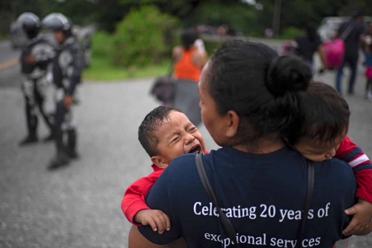 A migrant taking part in a caravan heading to the US, carries two toddlers on the road from Huixtla to Escuintla, in Chiapas state, Mexico, on June 9, 2022. Thousands of mostly Venezuelan migrants began receiving temporary Mexican visas Wednesday as they prepared to continue their trek toward the United States. The migrants had set up a temporary camp on a basketball court in the southern Mexican town of Huixtla, some 40 kilometers from where they began their journey on Monday close to the Guatemala border.