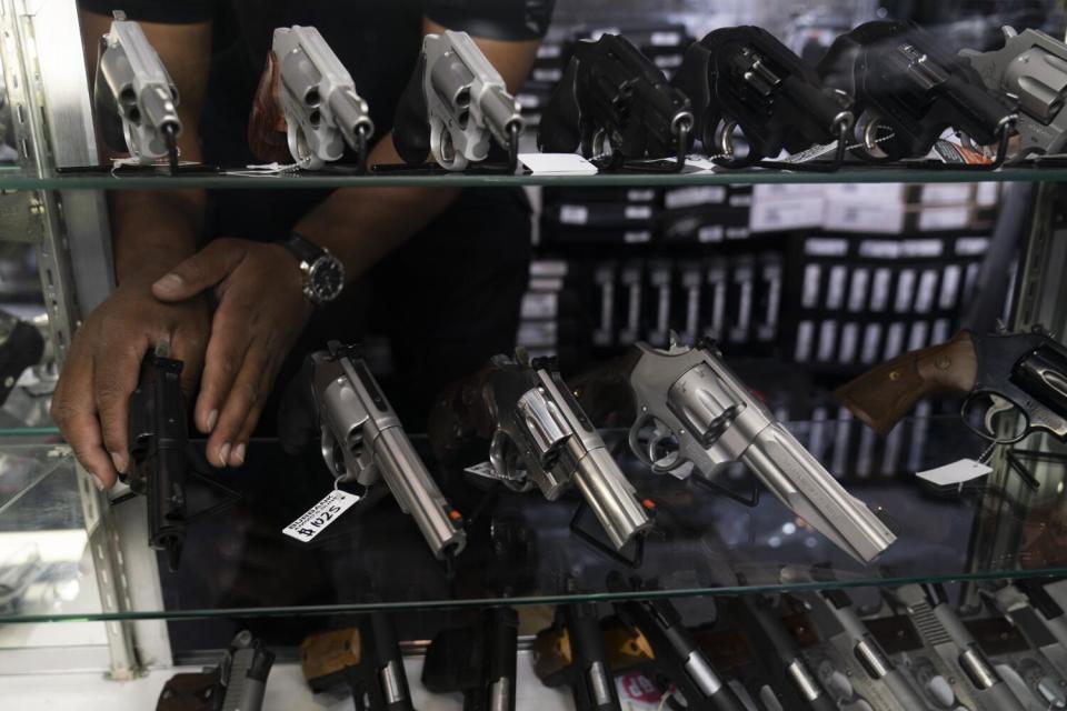 Sales associate Elsworth Andrews arranges guns on display at Burbank Ammo & Guns in Burbank.