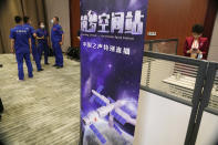 Workers prepare for the start of a press conference near a poster depicting the Chinese space station held at the Jiuquan Satellite Launch Center ahead of the Shenzhou-12 launch from Jiuquan in northwestern China's Gansu province on Wednesday, June 16, 2021. (AP Photo/Ng Han Guan)