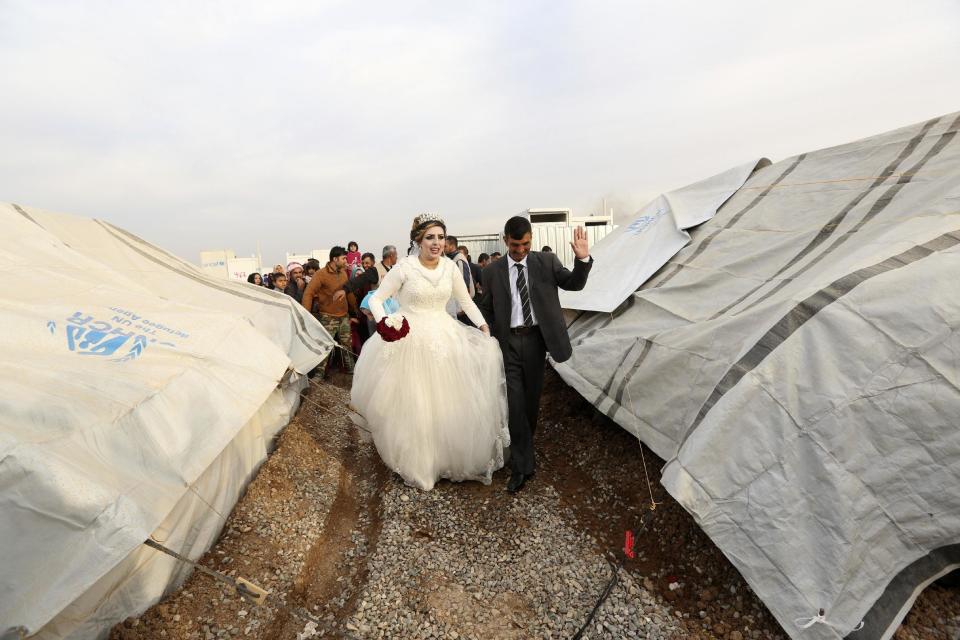 FILE - Iraqi internally displaced groom Jassim Mohammed walks with his bride, Amena Ali, during their wedding ceremony at a camp for internally displaced people, in Khazir, near Mosul, Iraq, Thursday, Dec. 8, 2016. (AP Photo/Hadi Mizban, File)