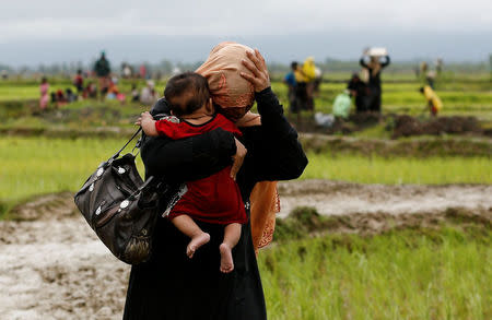 A Rohingya refugee woman carries a child while walking on the muddy road after travelling over the Bangladesh-Myanmar border in Teknaf, Bangladesh, September 1, 2017. REUTERS/Mohammad Ponir Hossain
