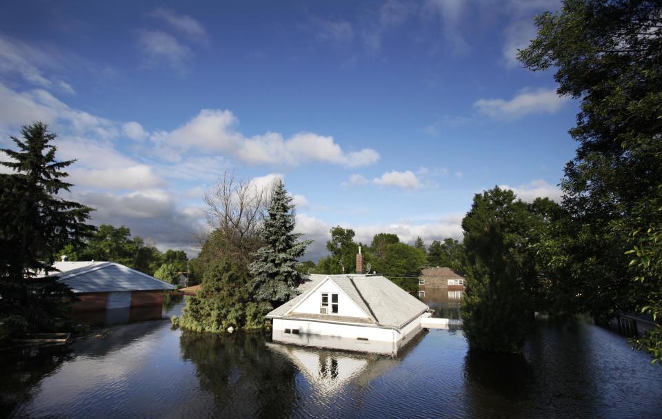 FILE - In this June 27, 2011 file photo, floodwaters from the Souris River surround homes near Minot State University in Minot, N.D. Global warming is rapidly turning America the beautiful into America the stormy, sneezy and dangerous, according to the National Climate Assessment report released Tuesday, May 6, 2014. (AP Photo/Charles Rex Arbogast)