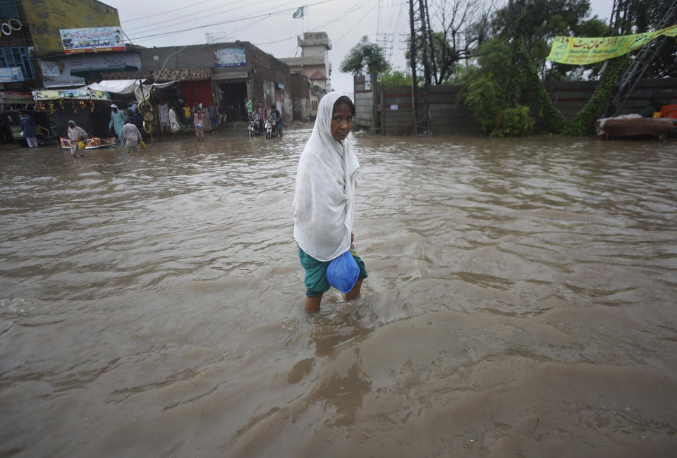 A woman wades through a flooded road after heavy rainfall in Lahore, Pakistan, Thursday, Aug. 20, 2020. Emergency workers say relentless monsoon rains kill some people and injure many in Pakistan's most populous Punjab province. (AP Photo/K.M. Chaudary)