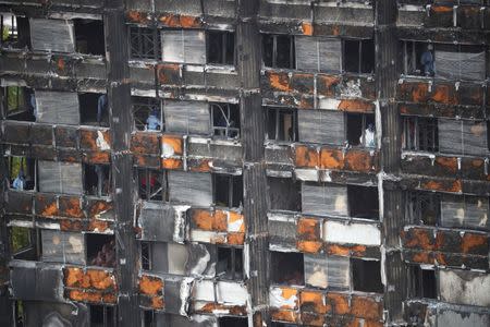 Workers stand inside the burnt out remains of the Grenfell tower in London, Britain, October 16, 2017. REUTERS/Hannah Mckay/Files