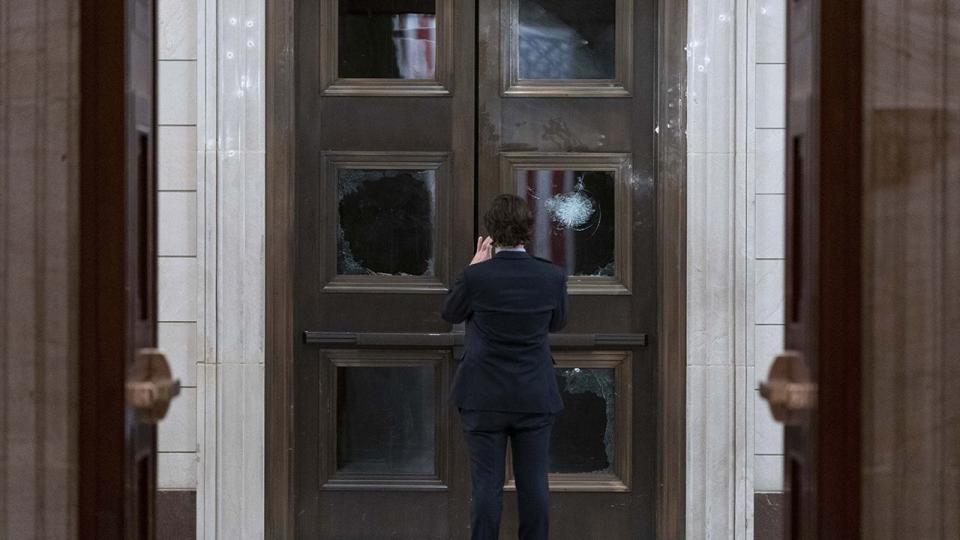 A man takes a photo of broken windows near the Rotunda in the early morning hours of Thursday, Jan. 7, 2021, after protesters stormed the Capitol in Washington, on Wednesday.