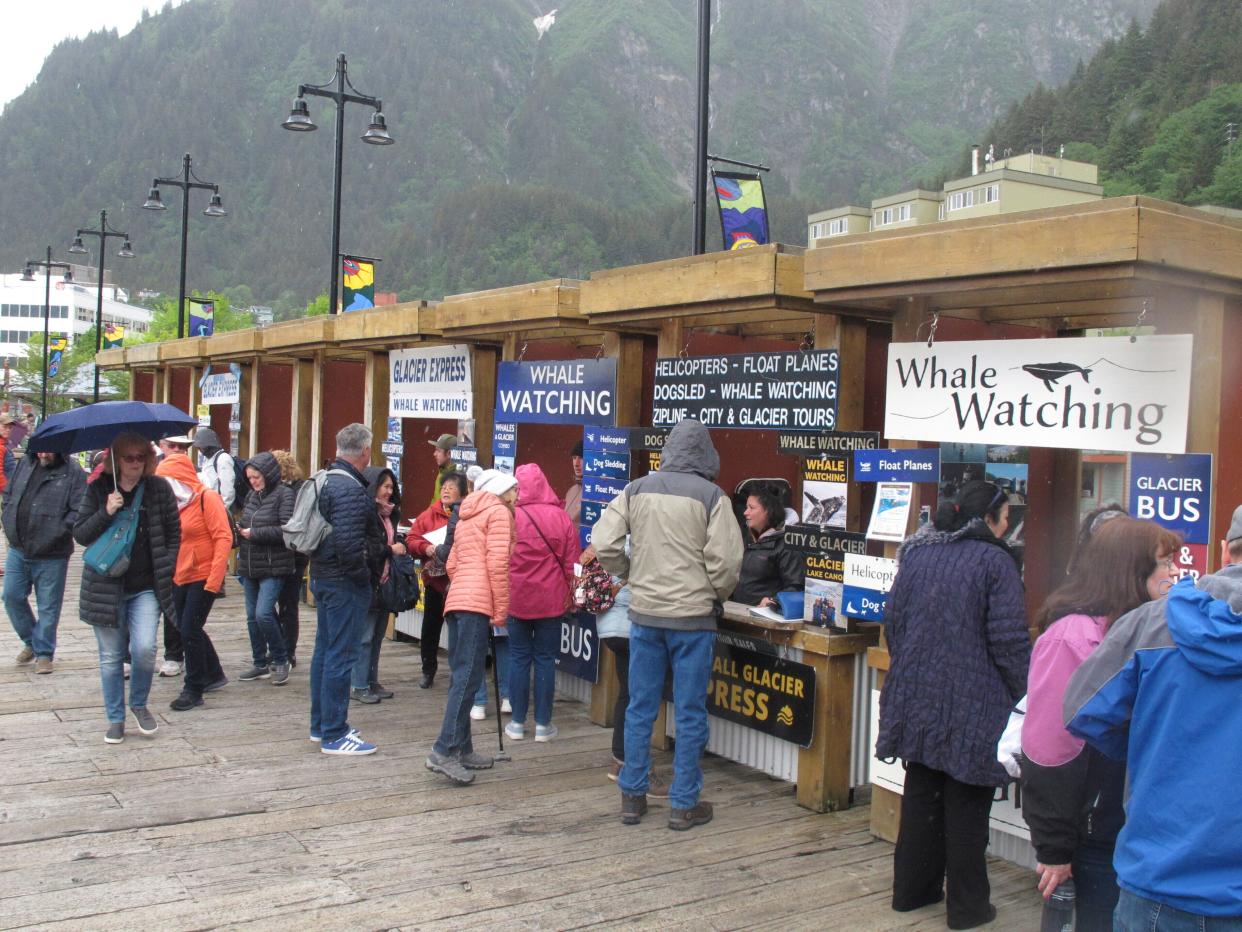 Tourists stop at booths along the sea walk on June 12, 2023, in downtown Juneau, Alaska, where they can book activities to do while they're in town.