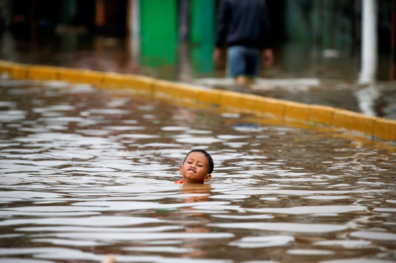 A boy swims in the floodwaters at the Jatinegara area after heavy rains in Jakarta