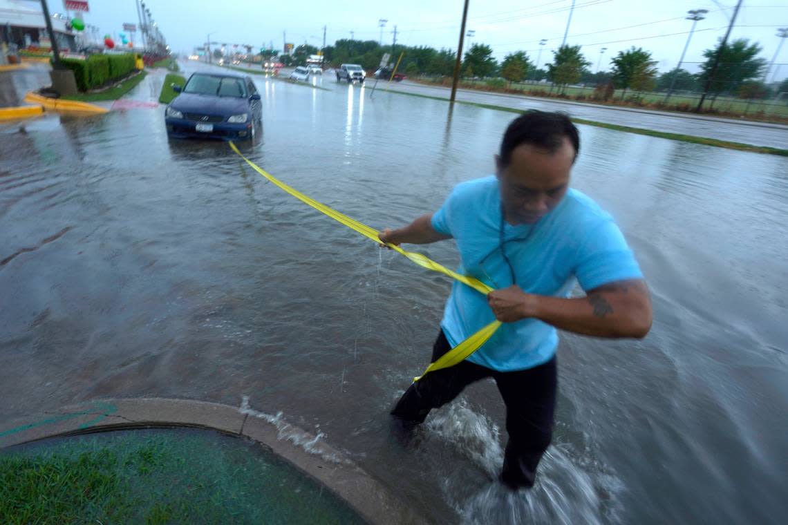 Mon Lun pulls a strap to his water stalled car before towing it out of receding flood waters in Dallas, Monday, Aug. 22, 2022. (AP Photo/LM Otero)