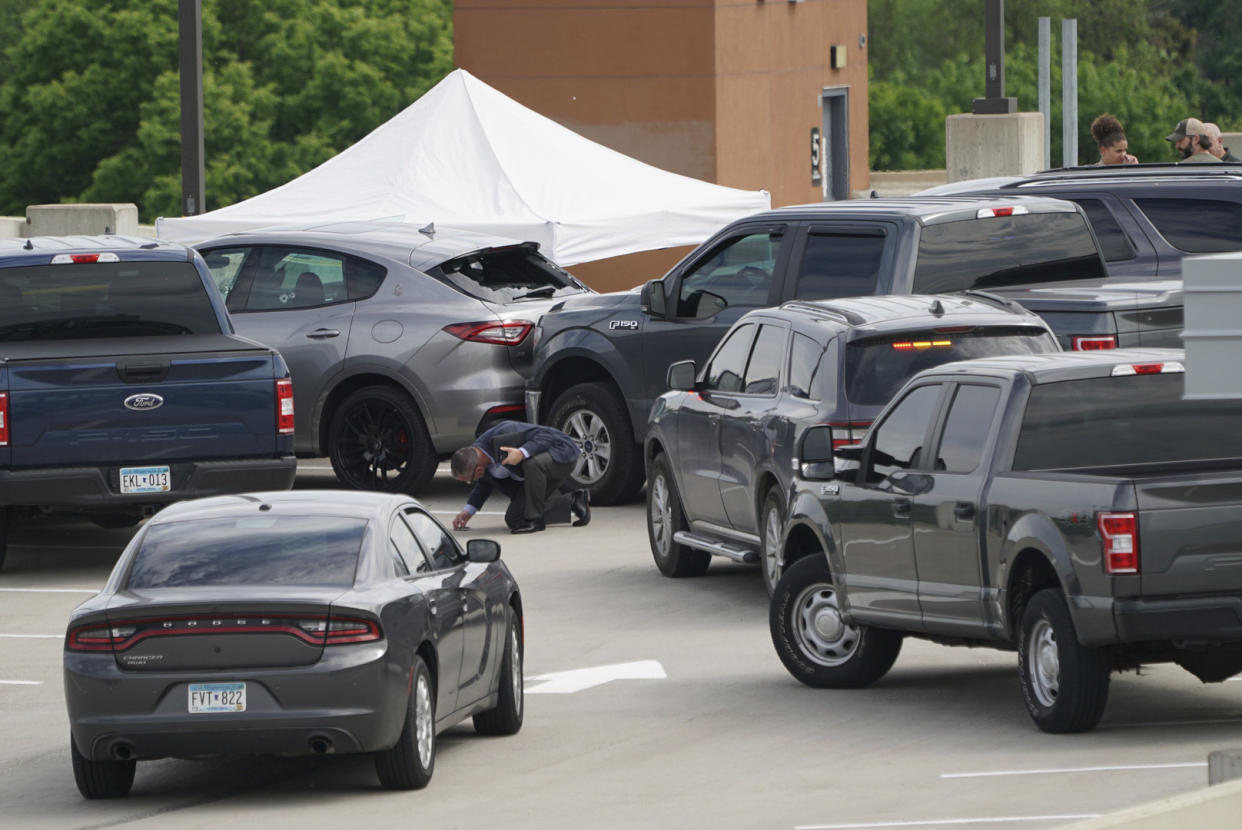 An investigator goes through the scene of crash believed to be part of an officer involved shooting on the top of a parking ramp in Minneapolis, Thursday June 3, 2021. One person was killed Thursday when authorities who were part of a task force that included U.S. Marshals fired their weapons after the person displayed a handgun in Minneapolis' Uptown neighborhood, the U.S. Marshals said. (Renee Jones Schneider/Star Tribune via AP)