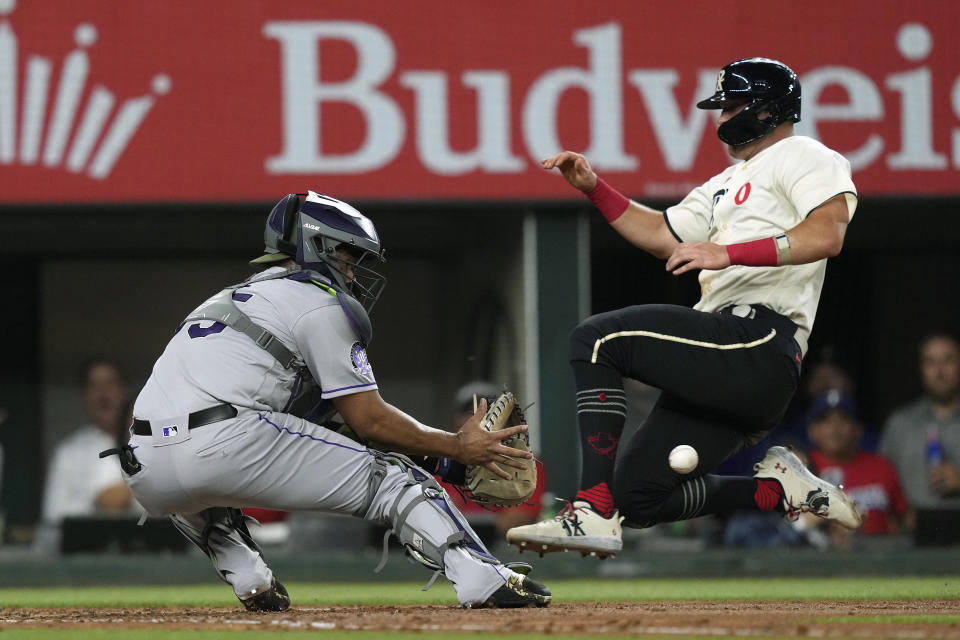 Texas Rangers Josh Jung, right, leaps into home plate as Colorado Rockies catcher Elias Diaz, left, reaches for a throw before putting on the tag for an out during the fourth inning of a baseball game in Arlington, Texas, Friday, May 19, 2023. Jung was caught while trying to score on a double by teammate Ezequiel Duran. (AP Photo/LM Otero)