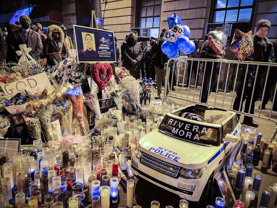 A vigil is held around a makeshift memorial outside the 32nd precinct honoring fallen NYPD officers Jason Rivera and Wilbert Mora in Harlem, Wednesday Jan. 26, 2022, in New York. (AP Photo/Bobby Caina Calvan)
