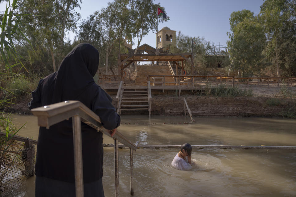 Olga Bokkas, a visitor from Connecticut, immerses herself in the waters of the Jordan River at the Qasr al-Yahud baptismal site, near the West Bank town of Jericho on Sunday, July 31, 2022. The river’s dwindling waters are sluggish and a dull brownish green in this area. (AP Photo/Oded Balilty)