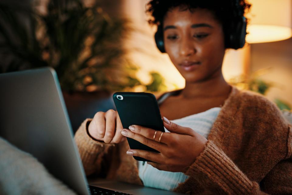 woman on laptop and phone wearing headphones