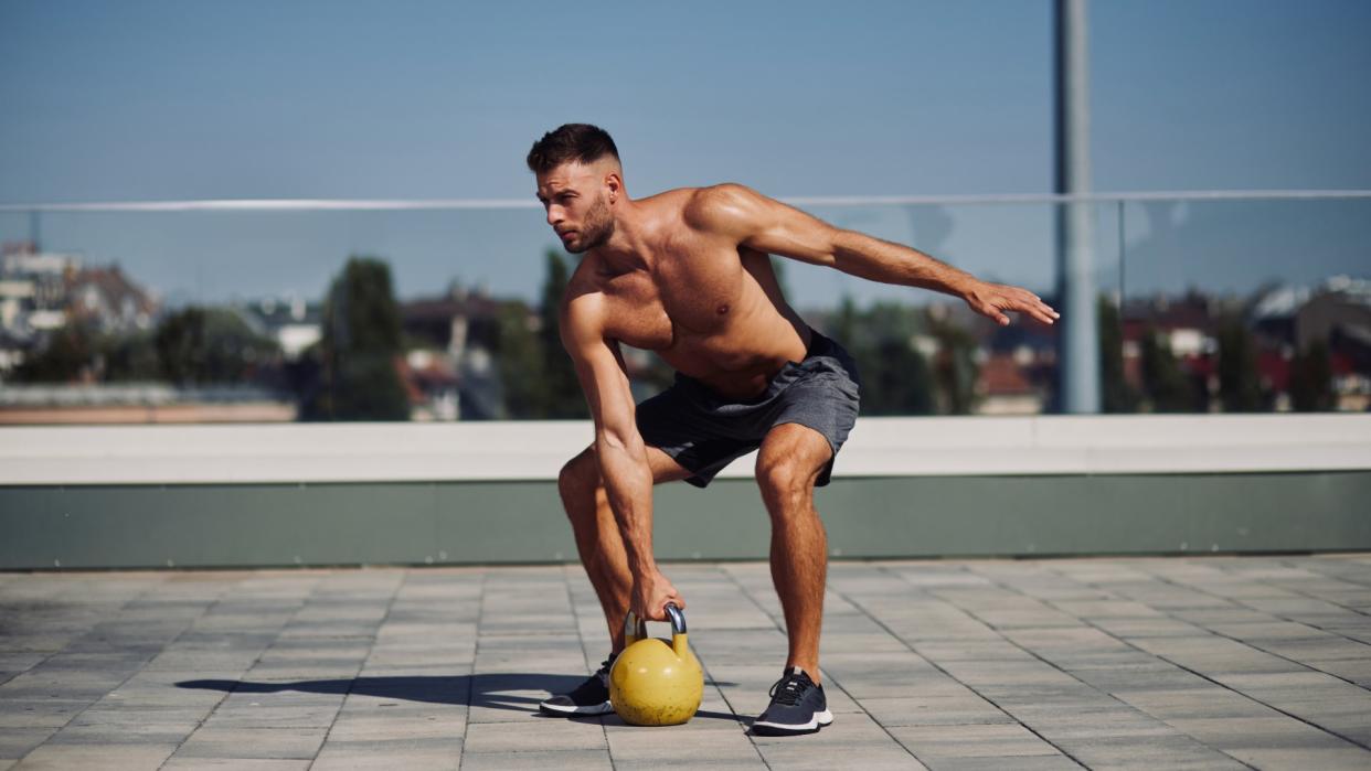  Man outdoors training holding a kettlebell in right hand . 
