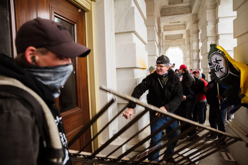 A member of a pro-Trump mob bashes an entrance of the Capitol Building in an attempt to gain access in Washington, DC.