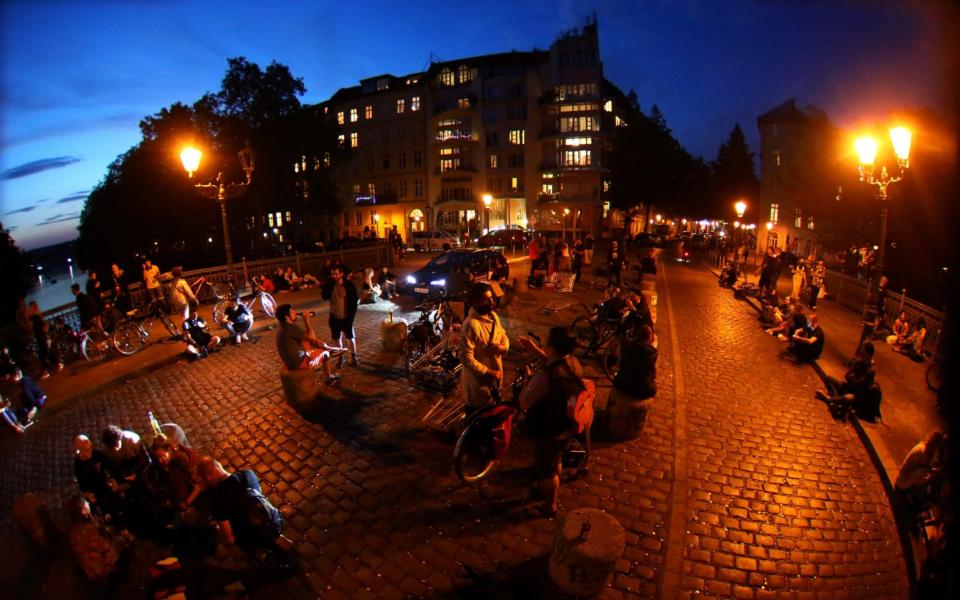 People sit after sunset at the admiral bridge, a popular meeting point for tourists and residents, amid the coronavirus outbreak - REUTERS/Hannibal Hanschke