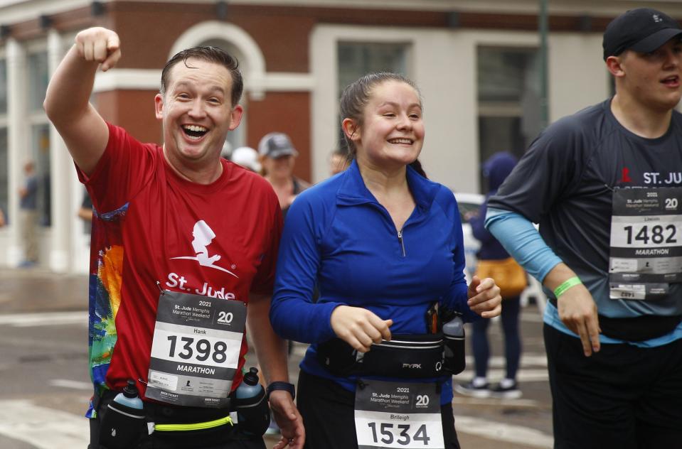 Hank Hayes, of Murfreesboro, Tennessee, points while running in the 2021 St. Jude Memphis Marathon on Saturday, Dec. 4, 2021 in Downtown Memphis.  Running with him are Brileigh Roach, middle, and Lincoln Sloan, both also from Murfreesboro.