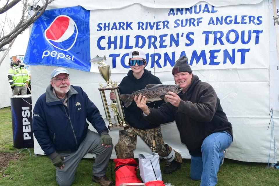 Justin Carey, 12, center, holds the winning 5-pound, 5-ounce tiger trout he caught in the Shark River Surf Angler's Spring Lake Kid's Trout Contest. He is flanked by club president Ken Morse on the left and club vice president Greg Hueth on the right.