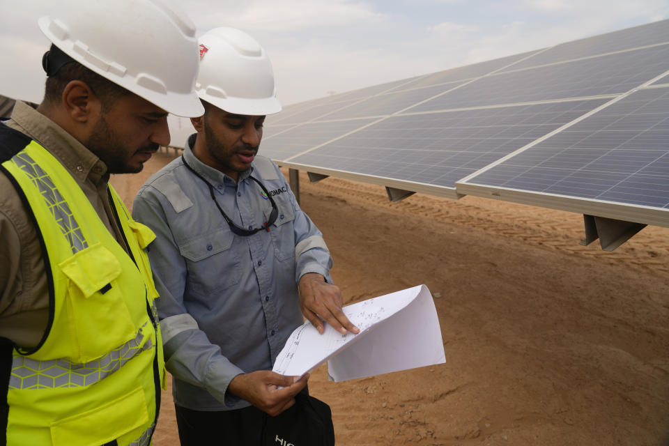 Engineers talk next to photovoltaic solar panels at Benban Solar Park, one of the world's largest solar power plants in the world, in Aswan, Egypt, Oct. 19, 2022. The Arab world’s most populous country is taking steps to convert to renewable energy. But the developing country, like others, faces obstacles in making the switch. (AP Photo/Amr Nabil)