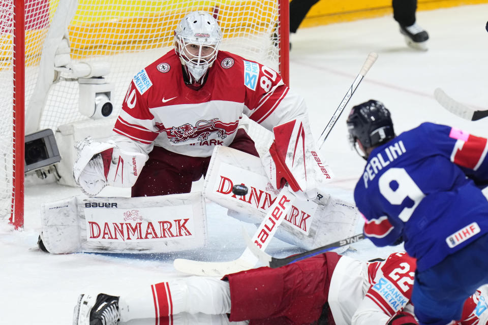 Britain's Brett Perlini, right, takes a shot at Denmark's goalkeeper Frederik Dichow during the preliminary round match between Great Britain and Denmark at the Ice Hockey World Championships in Prague, Czech Republic, Friday, May 17, 2024. (AP Photo/Petr David Josek)