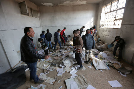 Students salvage books and items inside a classroom in 'Aisha Mother of the BelieversÕ school which was recently reopened after rebels took control of al-Rai town from Islamic State militants, Syria January 17, 2017. Picture taken January 17, 2017. REUTERS/Khalil Ashawi