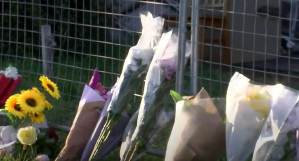 Flowers leaning against a temporary fence.