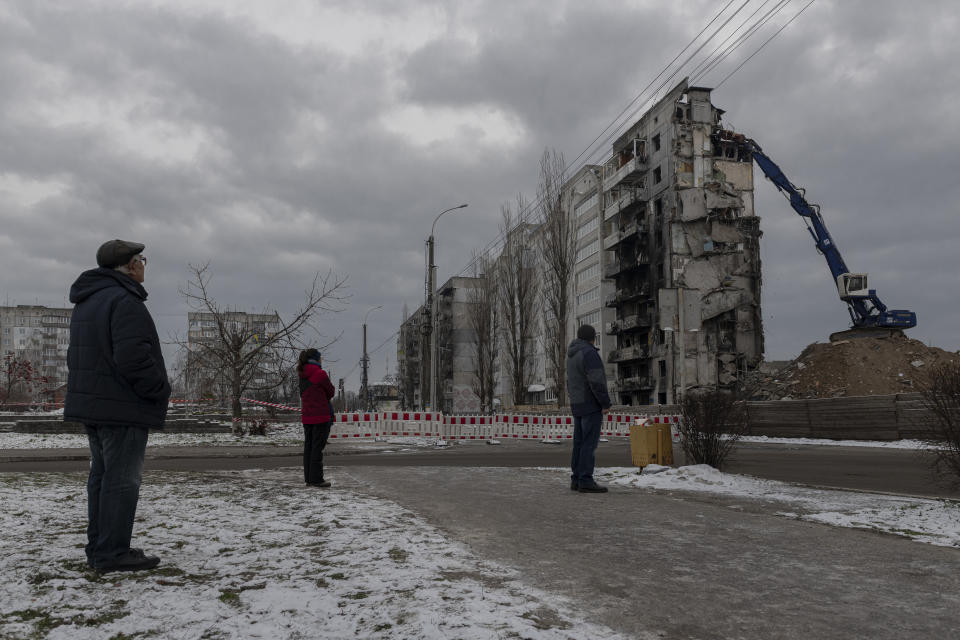 FILE - Local residents watch as a bombed building is dismantled in Borodyanka, Kyiv region, Ukraine, Tuesday, Dec. 13, 2022. When Federal Reserve's economists in the U.S. put together their forecasts a year ago they didn't foresee that Russia would send tens of thousands of troops into neighboring Ukraine. (AP Photo/Andrew Kravchenko, File)