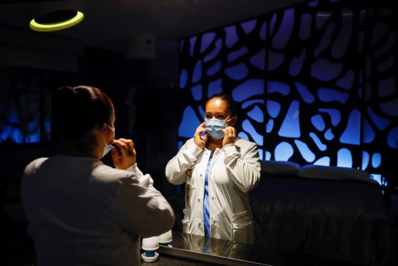 Nurse Gisela Hernandez, who has stayed away from her children for nearly two months to avoid infecting them because she feels inadequately protected, puts her face mask on before going to work, at her hotel room in Mexico City