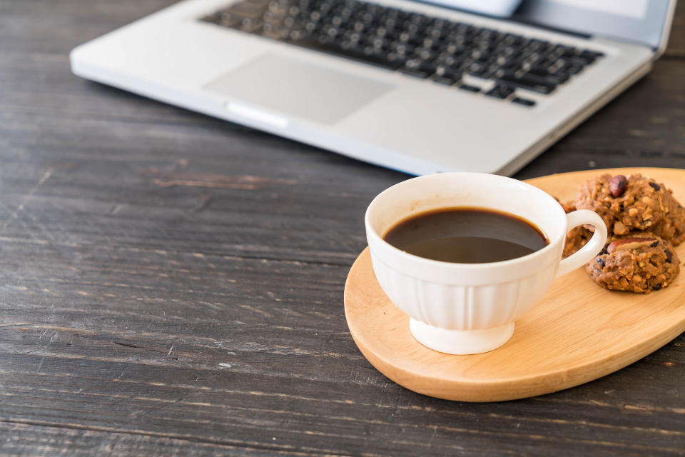 black coffee and cookies with laptop and note book on table