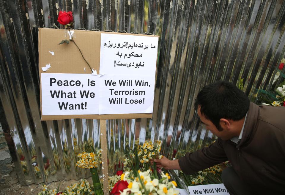 An Afghan member of a civil society organization puts flowers outside of the La Taverna du Liban restaurant, during an anti terrorism demonstration in Kabul, Afghanistan, Sunday, Jan. 19, 2014. Hundreds of Afghans gathered outside a Lebanese restaurant in Kabul on Sunday to protest against Taliban attack that killed 21 people. The assault Friday by a Taliban bomber and two gunmen against the La Taverna du Liban restaurant was deadliest single attack against foreign civilians in the course of a nearly 13-year U.S.-led war there now approaching its end. They chanted slogans against terrorism as they laid flowers at the site of the attack. The dead included 13 foreigners and eight Afghans, all civilians. The attack came as security has been deteriorating and apprehension has been growing among Afghans over their country's future as U.S.-led foreign forces prepare for a final withdrawal at the end of the year. (AP Photo/Massoud Hossaini)