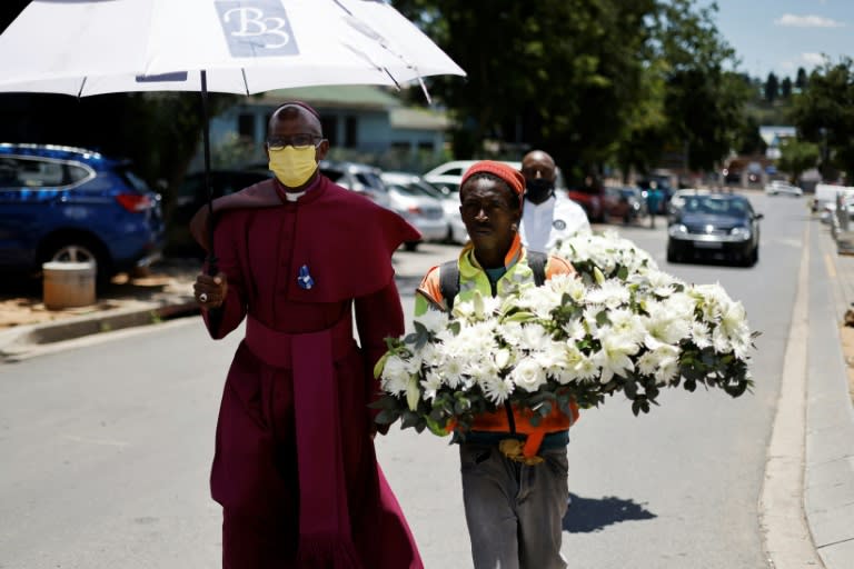 Johannesburg Bishop Stephen Moreo walks alongside a man bearing a wreath of flowers to Tutu's family home as those who knew him paid tribute to a man who was "the voice of the voiceless" (AFP/Marco LONGARI)