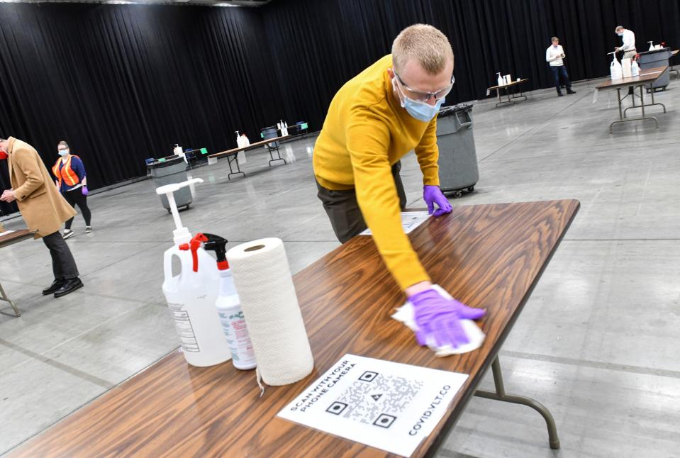 Josh Scholten cleans a testing station at the COVID-19 saliva testing site Wednesday, Oct. 28, 2020, at the River's Edge Convention Center in St. Cloud. 