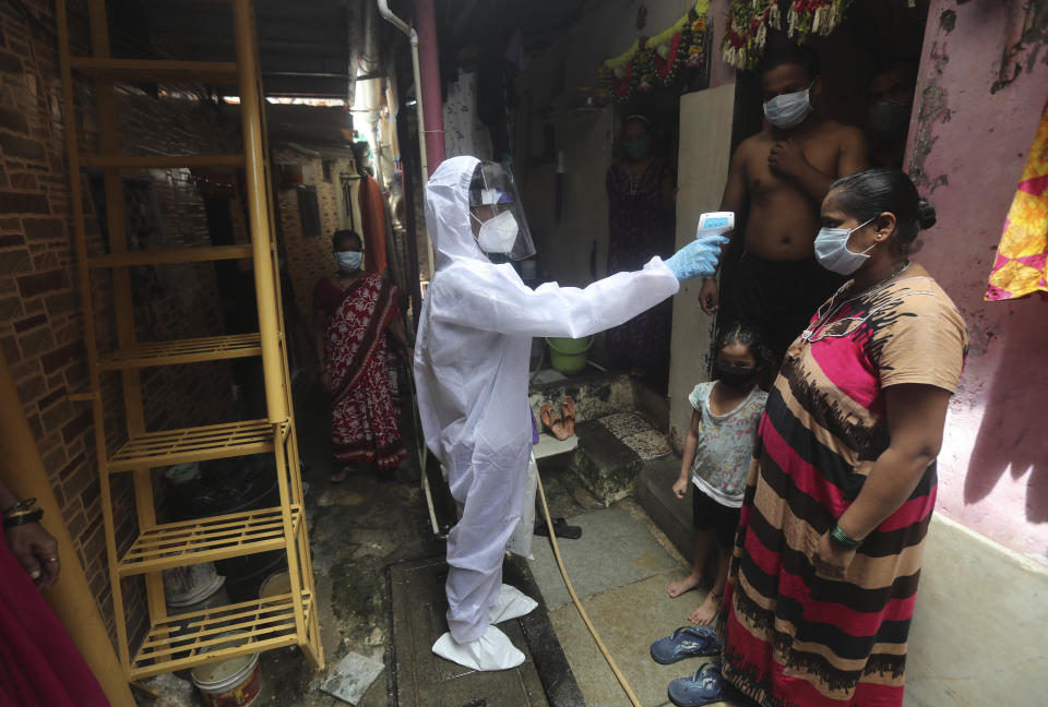 A health worker checks the temperature of a woman during a free medical checkup in a slum in Mumbai, India, Sunday, June 28, 2020. India is the fourth hardest-hit country by the COVID-19 pandemic in the world after the U.S., Russia and Brazil. (AP Photo/Rafiq Maqbool)