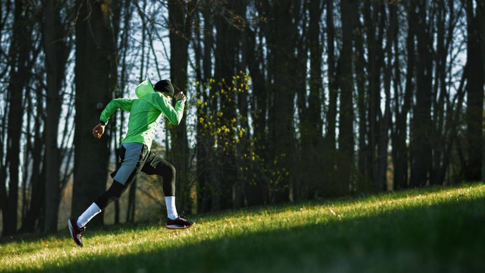 side view of an athlete young man running on a hill in mountain athletic male jogging in the park in the morning in a sunny day people, healthy lifestyle and sport concept