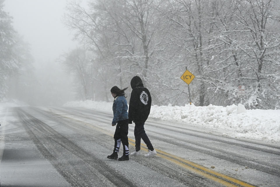 Two people cross the Sunrise Highway in the Cleveland National Forest, Wednesday, Feb. 7, 2024, in eastern San Diego county, Calif. According to the National Weather Service snow level is down to 4,500 feet in the San Diego county mountains (AP Photo/Denis Poroy)