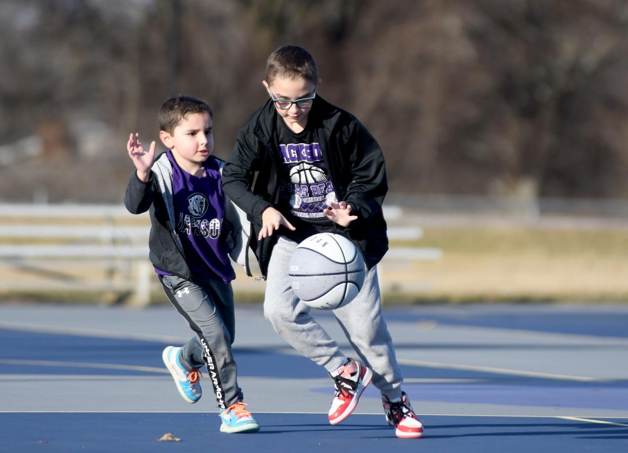 Maddox, 5, and brother Jordan Wright, 9, play a game of basketball on an unseasonably warm winter day at North Park in Jackson Township.