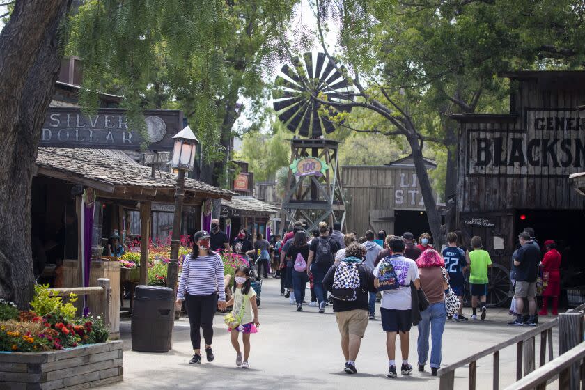 Buena Park, CA - May 29: Park-goers stroll through the Old West Ghost Town during the re-opening day at Knott's Berry Farm to the full public and celebrate the 100th anniversary of the park after the easing of coronavirus pandemic restrictions Saturday, May 29, 2021 in Buena Park, CA. This is the first time the broader public has been able to enter and enjoy the main park at Knott's Berry Farm. Knott's is also debuting a new ride called "Knots Betty Tales." (Allen J. Schaben / Los Angeles Times)