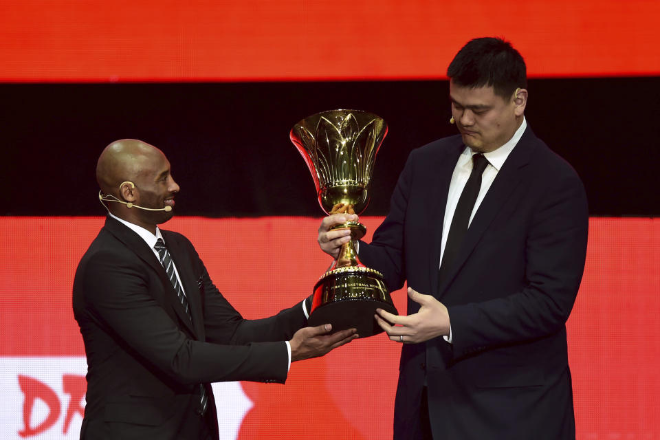 Former NBA basketball player and FIBA World Cup Ambassador Kobe Bryant, left, passes a trophy to former NBA basketball player and Chinese Basketball Association president Yao Ming during the draw ceremony for the 2019 FIBA Basketball World Cup in Shenzhen in southern China's Guangdong Province, Saturday, March 16, 2019. The competition will take place in 8 cities across China later this year. (Chinatopix via AP)