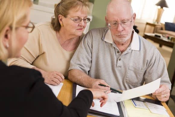 A senior couple examining paperwork with a financial adviser.